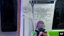 Un residente de Beijing usa el tren subterráneo en Beijing, usando su mascarilla para evitar el contagio del nuevo coronavirus en momentos de alerta por un repunte en las infecciones..