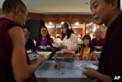 Guests and monks choose from a wide selection of homemade Tibetan dishes at the 18th birthday and enthronement ceremony for U.S.-born Buddhist lama, Jalue Dorje, in Isanti, Minnesota, Nov. 9, 2024.