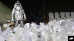 A worker in a special heat reflecting suit stands next to bags of seized cocaine, to be destroyed by fire at a police base in Lima, Peru, Oct. 11, 2016. The battle on drugs recently has moved to the docks where over 90 workers have been killed in crimes tied to smuggling.