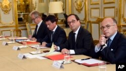 French President Francois Hollande, flanked by his Interior Minister Bernard Cazeneuve, right, and Prime Minister Manuel Valls, 2nd left, looks on during a meeting with French representatives of the different religion at the Elysee Palace in Paris, Wednes