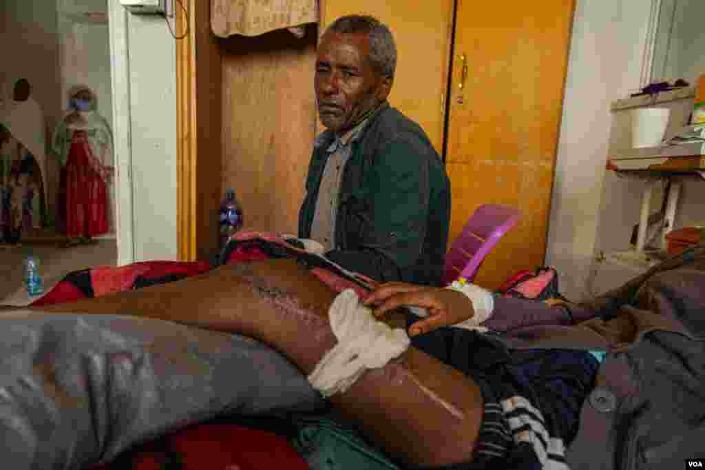 A father observes his teenage daughter’s wound June 4, 2021, in Mekelle, Ethiopia. She had been hit by a shot from a rifle.