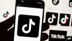 FILE - The TikTok logo is displayed on a mobile phone in front of a computer screen, Oct. 14, 2022, in Boston.