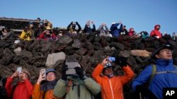 Pendaki menggunakan ponsel pintarnya untuk memotret matahari terbit di puncak Gunung Fuji, Selasa, 27 Agustus 2019, di Jepang. (Foto: AP/Jae C.Hong)