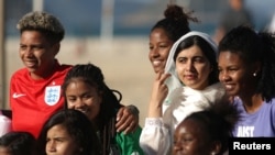 La ganadora del Premio Nobel de la Paz, Malala Yousafzai, posa con adolescentes de Complexo da Penha, que trabajan con la organización de fútbol Street Child United, en la playa de Copacabana en Río de Janeiro, Brasil, el 11 de julio de 2018.