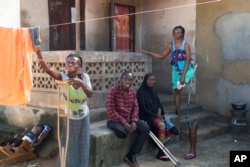 FILE - Amputees sit in front of their dwellings built by foreign NGOs in Freetown, Sierra Leone, Sept. 25, 2024.