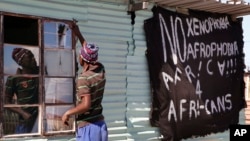 Un homme remplace une vitre brisée dans une taverne de la banlieue de Philippi, à la périphérie de Cape Town, en Afrique du Sud, le 20 avril 2015.