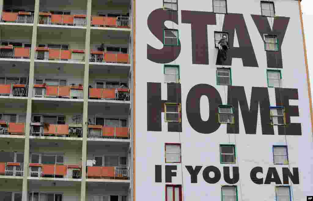 A billboard is installed on an apartment building in Cape Town, South Africa, before the country of 57 million people is placed under a nationwide lockdown for 21 days to fight the spread of the coronavirus.