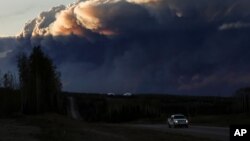 Smoke billows from the Fort McMurray wildfires as a truck drives down the highway in Kinosis, Alberta.