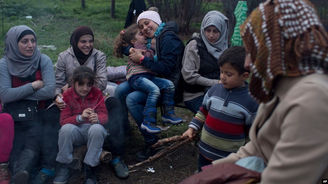 Stranded in the northern Greek border station of Idomeni for 15 days, Syrian refugees sit next to a fire as they wait to be allowed to cross to Macedonia, March 5, 2016.