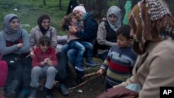 Stranded in the northern Greek border station of Idomeni for 15 days, Syrian refugees sit next to a fire as they wait to be allowed to cross to Macedonia, March 5, 2016.