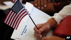 FILE - A soon-to-be U.S. citizen holds an American flag and the words to "The Star-Spangled Banner" before the start of a naturalization ceremony at the U.S. Citizenship and Immigration Services field office in Miami, Aug. 16, 2019.