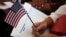 FILE - A soon-to-be U.S. citizen holds an American flag and the words to "The Star-Spangled Banner" before the start of a naturalization ceremony at the U.S. Citizenship and Immigration Services field office in Miami, Aug. 16, 2019.