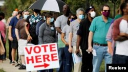 Voters wait in line to enter a polling place and cast their ballots on the first day of the state's in-person early voting for the general elections in Durham, North Carolina, Oct. 15, 2020.