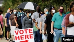 Voters wait in line to enter a polling place and cast their ballots on the first day of the state's in-person early voting for the general elections in Durham, North Carolina, Oct. 15, 2020.