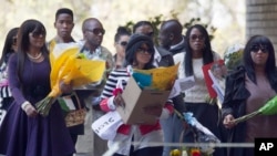 A group of unidentified relatives carry bunches of flowers that were left by wellwishers into the Mediclinic Heart Hospital where former South African President Nelson Mandela is being treated in Pretoria, South Africa, June 27, 2013. 