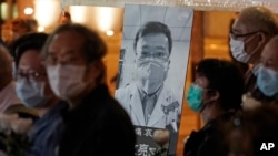 FILE - In this Feb. 7, 2020, photo, people in Hong Kong attend a vigil for Chinese doctor Li Wenliang, who was reprimanded for warning about the outbreak of the new coronavirus.