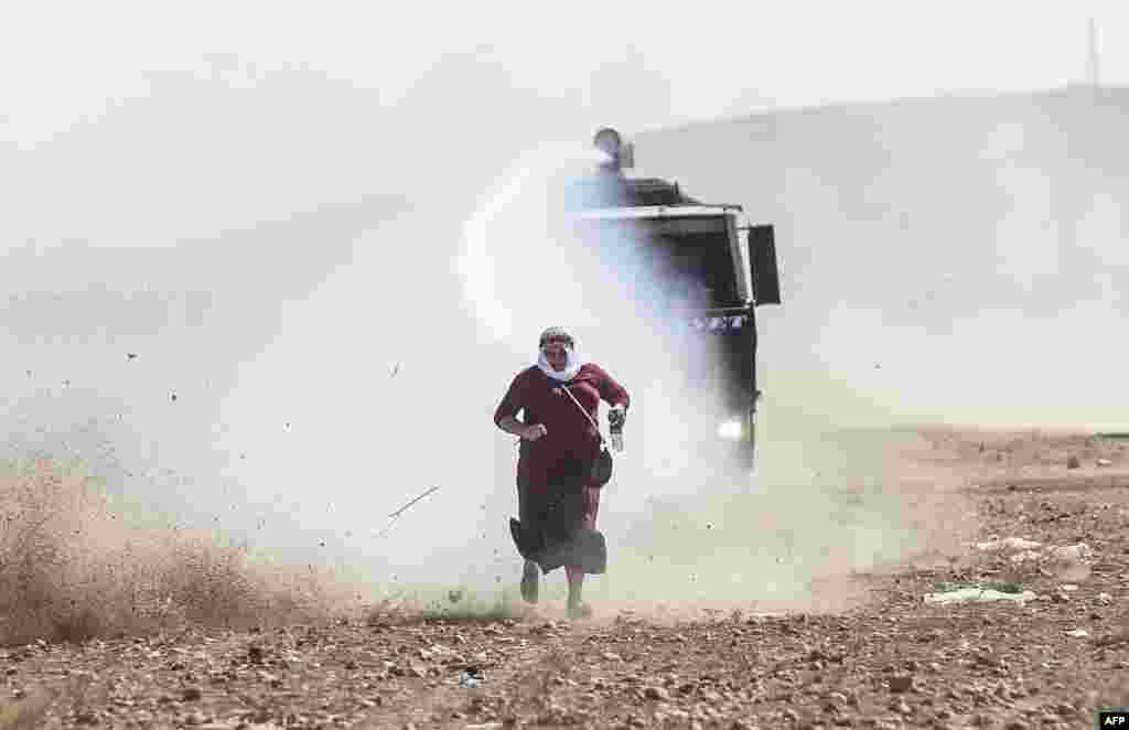 A Kurdish woman runs away from a water cannon near the Syrian border after Turkish authorities temporarily closed the border at the southeastern town of Suruc in Sanliurfa province. 