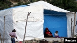 FILE - Internally displaced refugees rest near their tents in Rihaniyya camp in northern Syria's Latakia province, May 2, 2015. Six died in a June 1 fire at another camp in Lebanon.