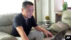 FILE - In this Sept. 18, 2012, file photo, veteran rights activist Huang Qi works on his laptop in his home in Chengdu in southwestern Sichuan province. 