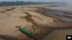 Reis Santo Vieira paints a boat on a dry part of the Madeira River, a tributary of the Amazon River, during the dry season in Humaita, Amazonas state, Brazil, Sept. 7, 2024. 