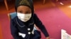 Amira Hassan, of Burnsville, Minnesota, plays in the waiting room at the specialty clinic at Children's Minnesota in Minneapolis, Minnesota, May 2, 2017. Amira went to the hospital's clinic for a routine wellness check, but had to wear a mask to protect her from measles after an outbreak.