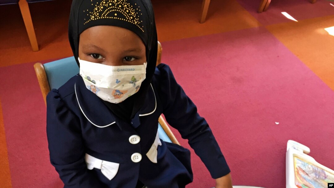 Amira Hassan, of Burnsville, Minnesota, plays in the waiting room at the specialty clinic at Children's Minnesota in Minneapolis, Minnesota, May 2, 2017. Amira went to the hospital's clinic for a routine wellness check, but had to wear a mask to protect her from measles after an outbreak.
