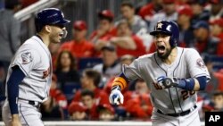 El venezolano Robinson Chirinos, de los Astros de Houston, festeja con el boricua Carlos Correa, luego de conectar un jonrón en el cuarto juego de la Serie Mundial ante los Nacionales de Washington, el sábado 26 de octubre de 2019 (AP Foto/Patrick Semansky).