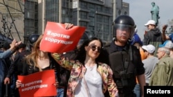 FILE - Policemen detain demonstrators during a protest in Moscow, Russia, May 5, 2018. The posters reads "I am against corruption."