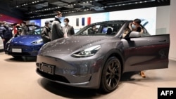 People look at a Tesla Model Y car at a Tesla showroom in Beijing on January 5, 2021. (Photo by WANG Zhao / AFP)