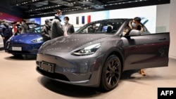 People look at a Tesla Model Y car at a Tesla showroom in Beijing on January 5, 2021. (Photo by WANG Zhao / AFP)