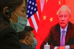 FILE - Attendees masked to curb the spread of the coronavirus sit near a screen showing China's Ambassador to the U.S. Cui Tiankai at the Lanting Forum on improving China-U.S. relations, at the Ministry of Foreign Affairs in Beijing, Feb. 22, 2021.