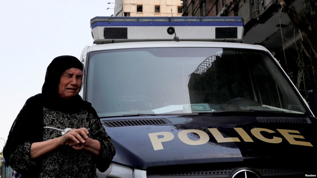 Seorang perempuan Mesir menangis saat melewati mobil polisi yang terparkir di depan Lembaga Kanker Nasional yang bagian depan rusak akibat ledakan bom mobil, di Kairo, Mesir, 5 Agustus 2019. 