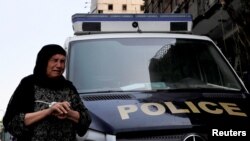 Seorang perempuan Mesir menangis saat melewati mobil polisi yang terparkir di depan Lembaga Kanker Nasional yang bagian depan rusak akibat ledakan bom mobil, di Kairo, Mesir, 5 Agustus 2019. 