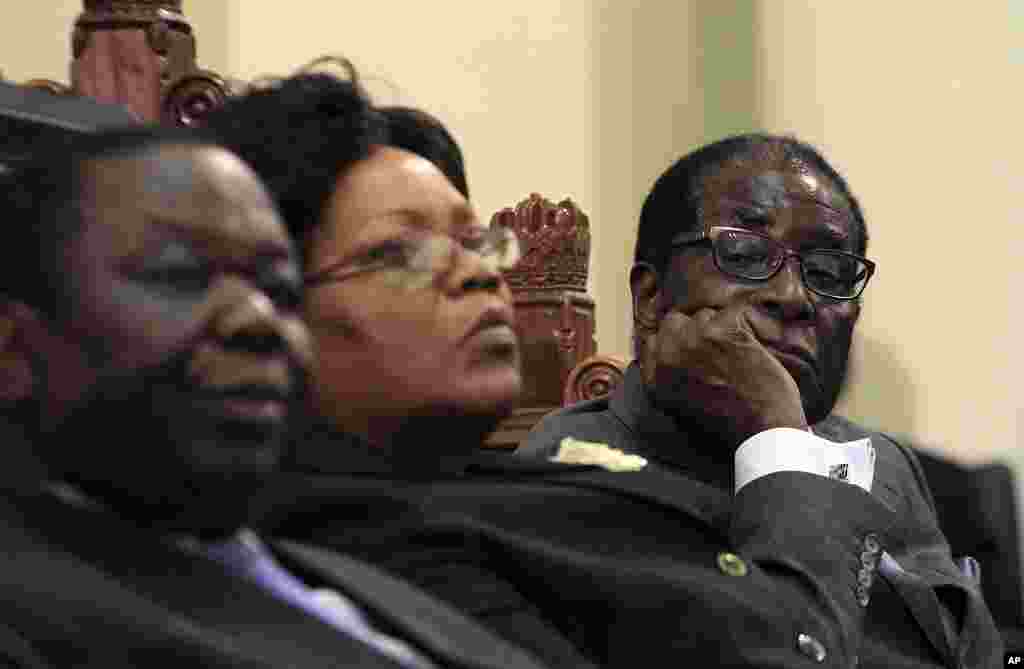 Zimbabwean President Robert Mugabe (R) listens as Finance Minister Tendai Biti delivers his budget speech in parliament in Harare, while Prime Minister Morgan Tsvangirai (L) and Vice President Joice Mjuru (C) look on, November 24, 2011. (AP)