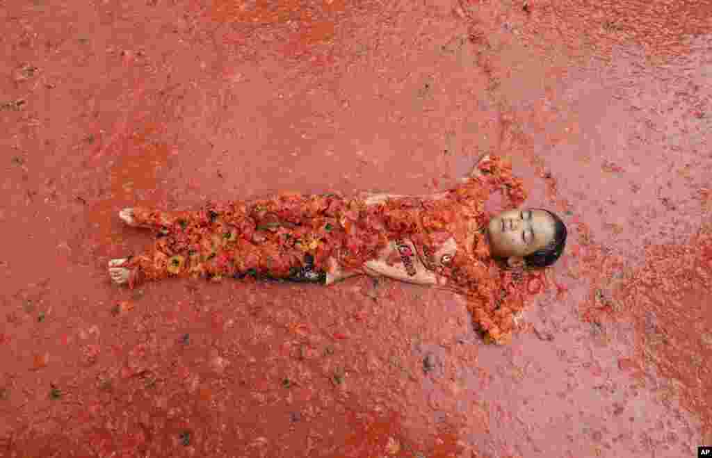 خوابیدن پسر بچه در استخری پر از گوجه فرنگی در فستیوال گوجه فرنگی در کره جنوبی