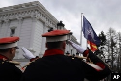 Macedonian soldiers salute as the NATO flag raising in front of the government building during a ceremony in Skopje, Feb. 12, 2019.