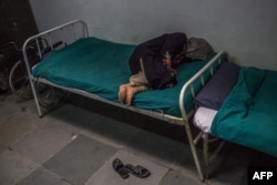 FILE - A Kashmiri patient suffering from symptoms of schizophrenia lies on a bed and periodically shouts to medical staff after being brought by relatives to the casualty ward at the Psychiatric Diseases hospital in Srinagar, Nov. 20, 2015.