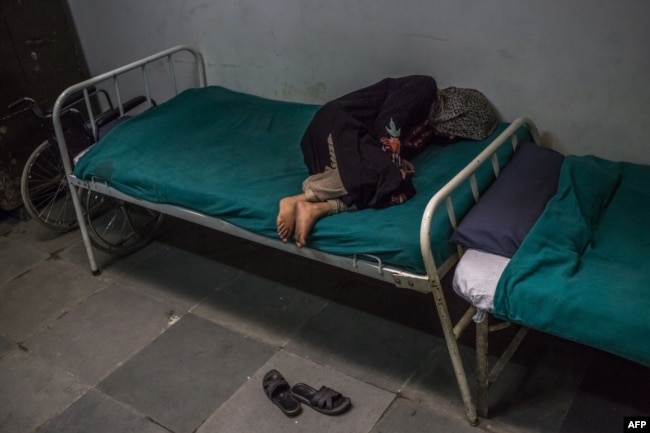 FILE - A Kashmiri patient suffering from symptoms of schizophrenia lies on a bed and periodically shouts to medical staff after being brought by relatives to the casualty ward at the Psychiatric Diseases hospital in Srinagar, Nov. 20, 2015.