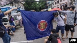 资料照：2021年6月14日，在仰光参加反对军事政变快闪示威的抗议者准备焚烧东盟旗帜（法新社）。