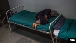 FILE - A Kashmiri patient suffering from symptoms of schizophrenia lies on a bed and periodically shouts to medical staff after being brought by relatives to the casualty ward at the Psychiatric Diseases hospital in Srinagar, Nov. 20, 2015. 