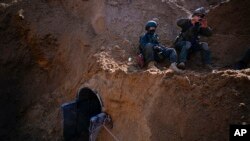 FILE - Israeli soldiers guard a crater-like hole giving way to a small tunnel entrance in an UNRWA compound beneath the main headquarters of the U.N. agency that the military says Hamas militants used to attack its forces during a ground operation in Gaza, February 8, 2024. 