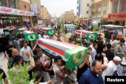 Mourners carry the coffins of fighters from Iraqi paramilitary troops who were killed in a battle against the Islamic State in the ancient city of Hatra, south of Mosul, during the funeral in Najaf, Iraq, April 27, 2017.