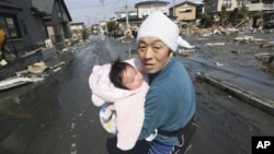 Upon hearing another tsunami warning, a father tries to flee for safety with his just reunited four-month-old baby girl who was spotted by Japan's Self-Defense Force member in the rubble of tsunami-torn Ishinomaki Monday, March 14, 2011.