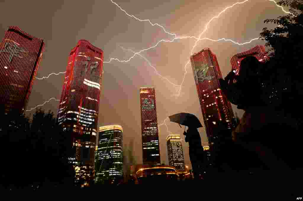 People look at buildings displaying a light show on the eve of the 100th anniversary of the Chinese Communist Party in Beijing.