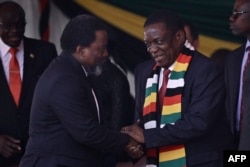 Zimbabwe President Emmerson Mnangagwa (R) receives D.R. Congo former president Joseph Kabila on September 14, 2019, during the farewell ceremony for the late former Zimbabwe president at the capital Harare's National Sports Stadium