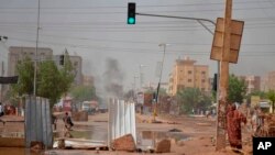 Smoke rises behind barricades laid by protesters to block a street in the Sudanese capital Khartoum to stop military vehicles from driving through the area on June 5, 2019.