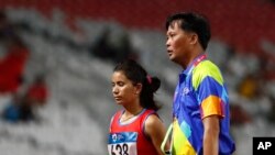 Pelari Nepal, Bishwarupa Budha, dikawal keluar jalur lomba lari setelah dia dikeluarkan dari final nomor lari 10.000 meter putri di lomba atletik Asian Games ke-18, di Jakarta, 26 Agustus 2018.