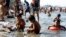 Children play with sand among garbage washed ashore as their family bathe in the waters of the Manila Bay during Easter Sunday in Manila, Mar. 31, 2013. 