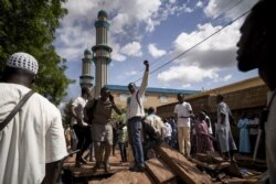 FILE - Protesters gestures on a barricade put up in front of the Salam mosque of Badalabougou, where the influent Imam Mahmoud Dicko led a prayer dedicated to the victims of clashes in Bamako, July 12, 2020.