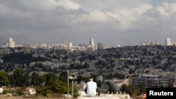 A view of Jerusalem is seen in the background as a man sits in Giv'at HaMatos, a neighborhood on the southern fringes of Jerusalem's city limits where Israel has decided to move forward on a settler housing project, Oct. 2, 2014. 